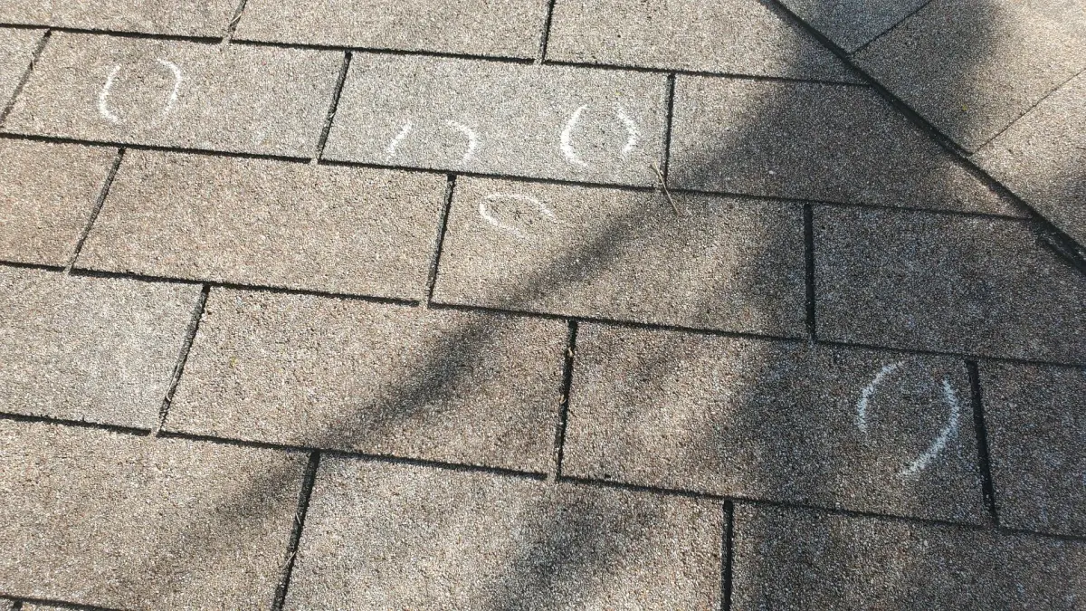 Hail strikes circled in chalk on a roof to document storm damage for an insurance claim