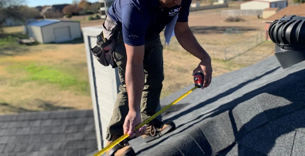 TXR roofer measuring shingles with a tape measure during a roof inspection